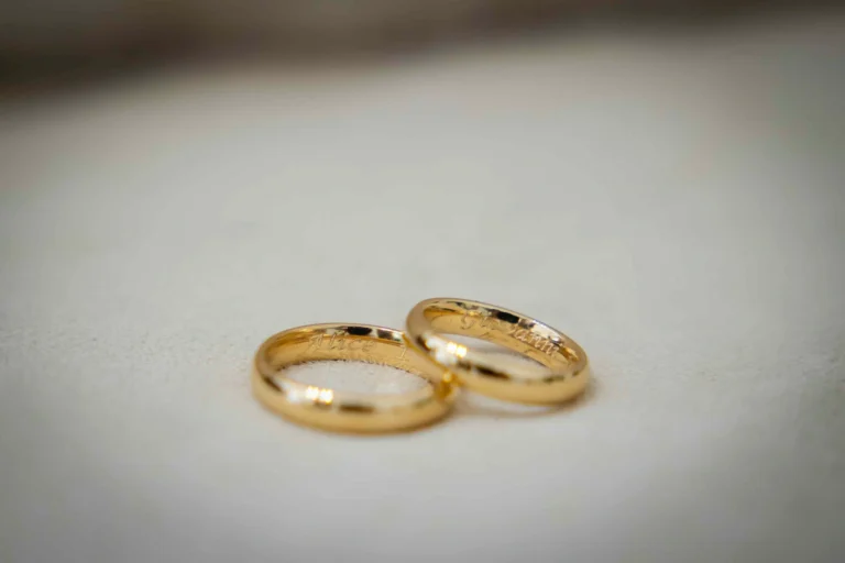 Primo piano di due fedi nuziali color oro su cui sono incisi i nomi Alice e Giovanni